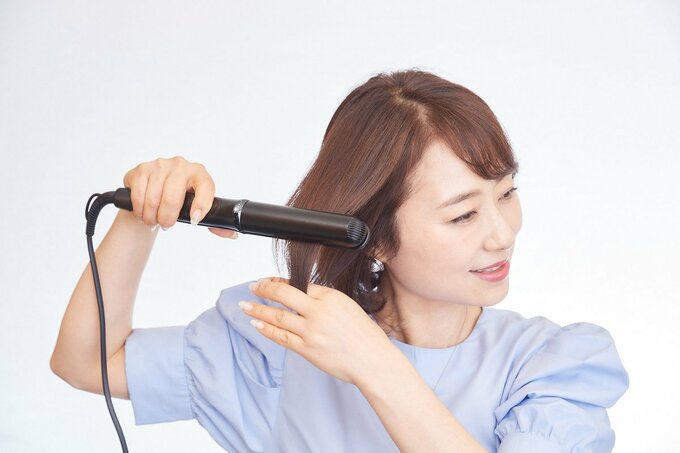ヘアアイロンをする女性