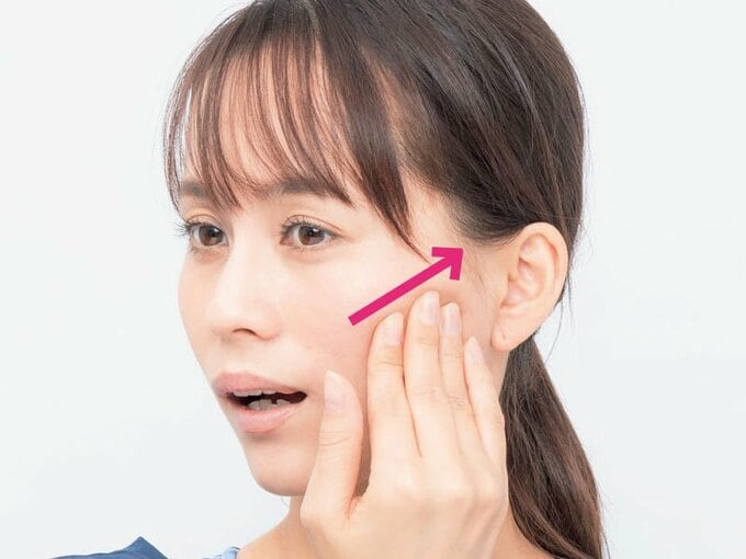 頬を手で押す女性