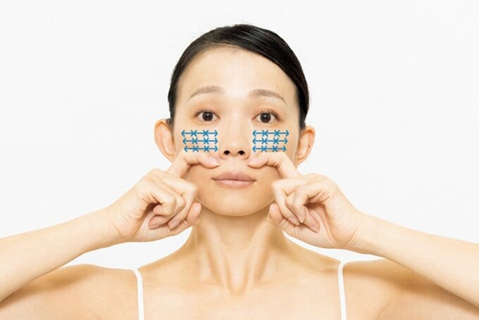 人さし指を曲げ、頬をマッサージする女性