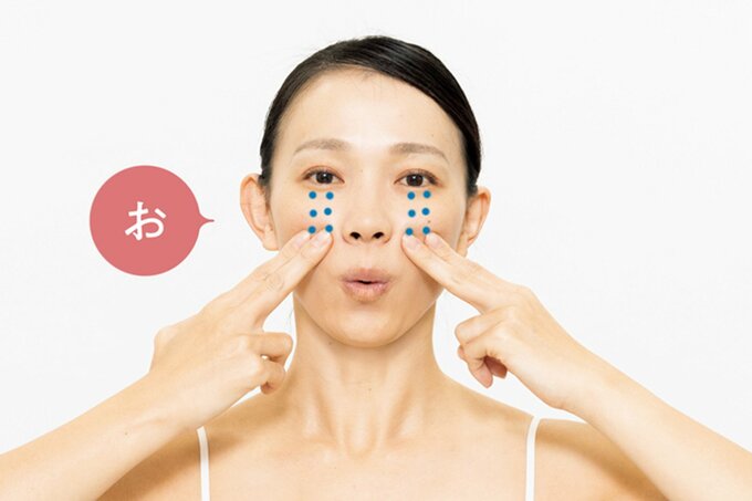 人さし指で頬を押しながら「お」と発声する女性