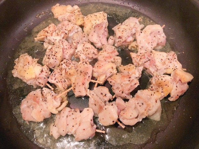 爪楊枝を刺した鶏肉を焼く様子
