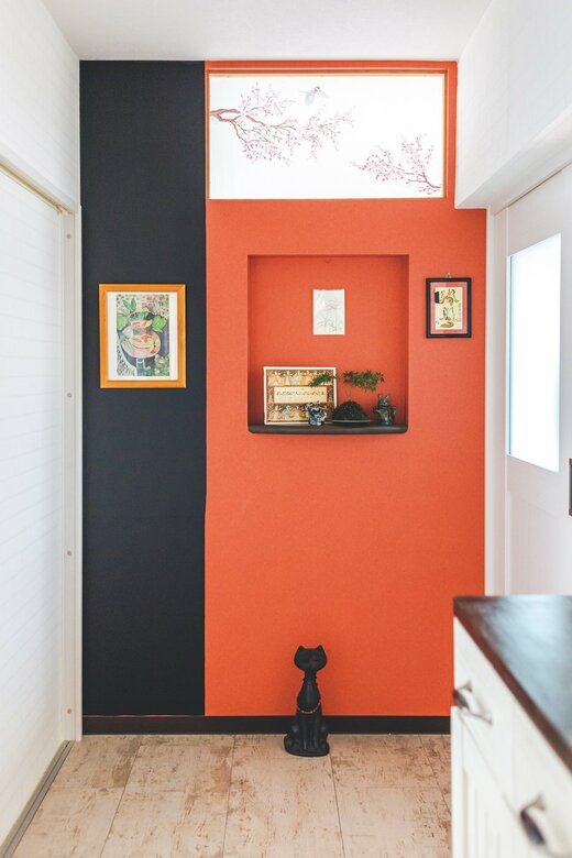 オレンジの壁紙一角に黒板シートをはった玄関の壁
