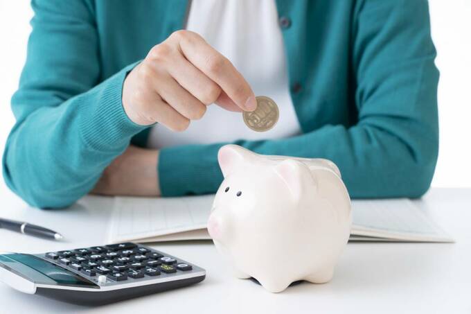 ブタの貯金箱にお金を入れる様子