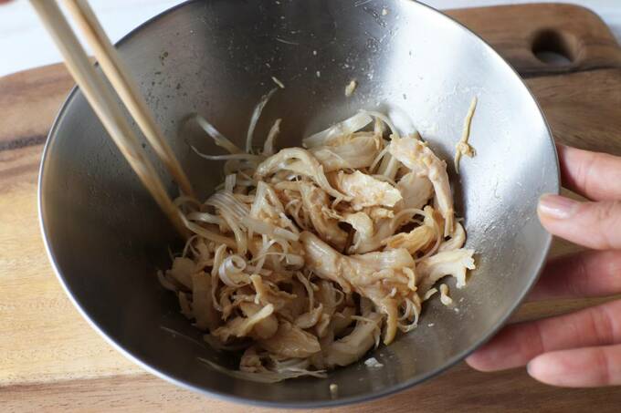 チキンと水気を切った長ネギをボウルに入れ和える様子