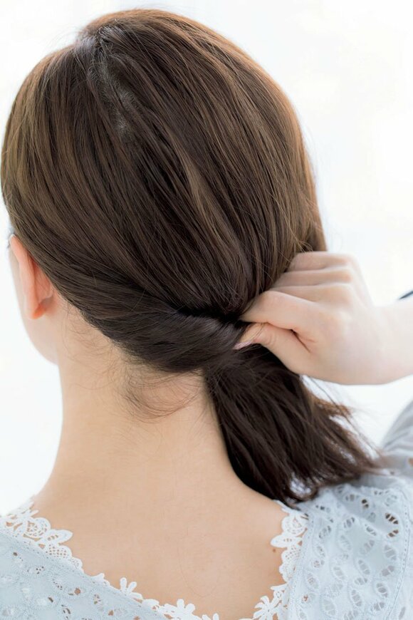 3側の髪を後ろにし、軽くねじりながら引っぱって7側の下に持っていく様子