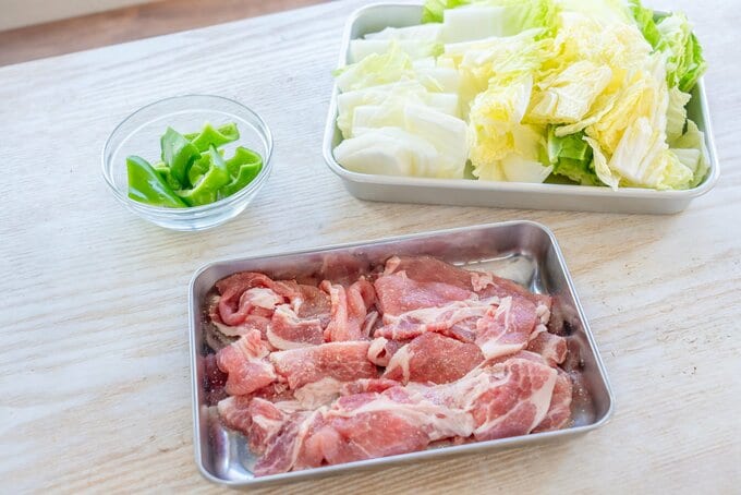 （1）豚肉は4〜5cm幅に切る。酒、塩・こしょうを振る。白菜はざく切りにする。 ピーマンは縦半分に切って種やわたを除き、大きめのひと口大に切る。