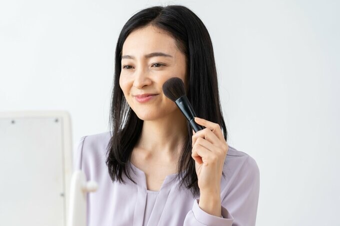 メイクブラシでパウダーを塗る女性