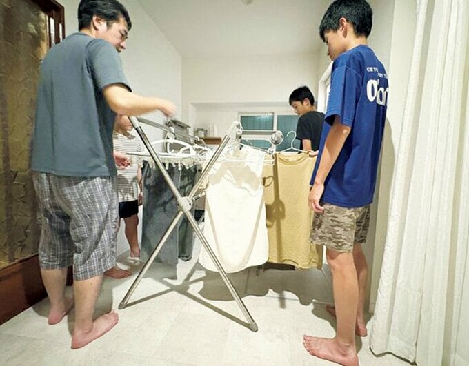 洗濯物を干す成人男性と3人の子ども