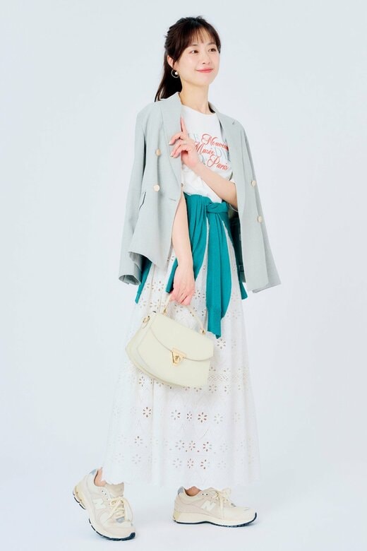 肩にかけたジャケットに手を当てて横向きに建つ女性