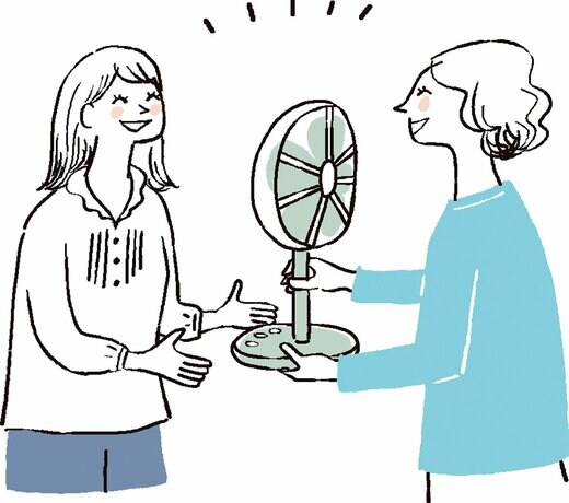 扇風機を手渡す女性と受け取る女性