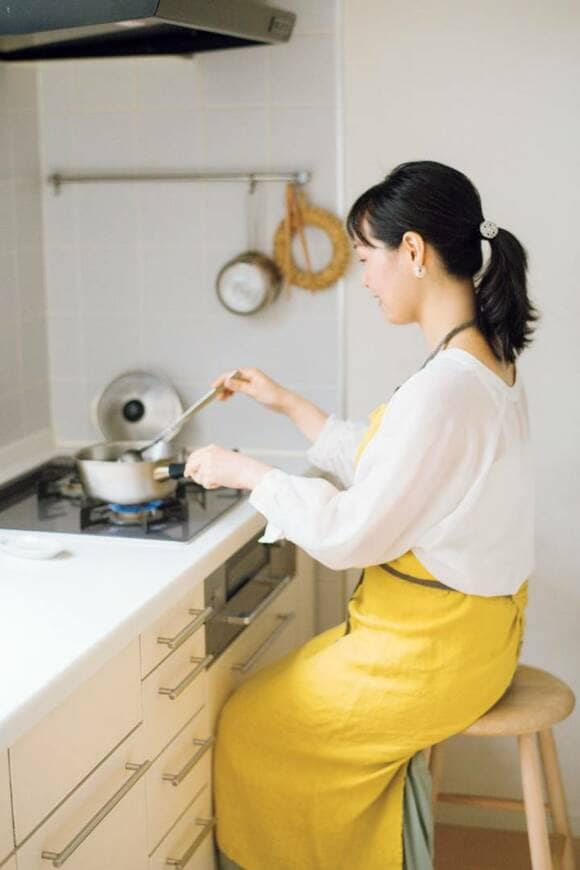 イスに座って料理をする女性