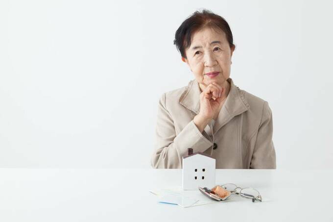 家の模型の前で悩む女性