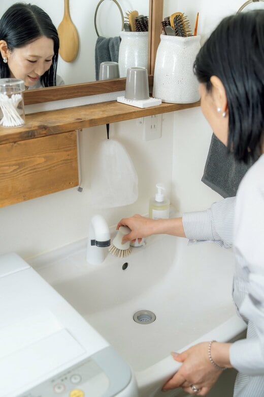 女性が洗面台の蛇口回りを掃除する様子