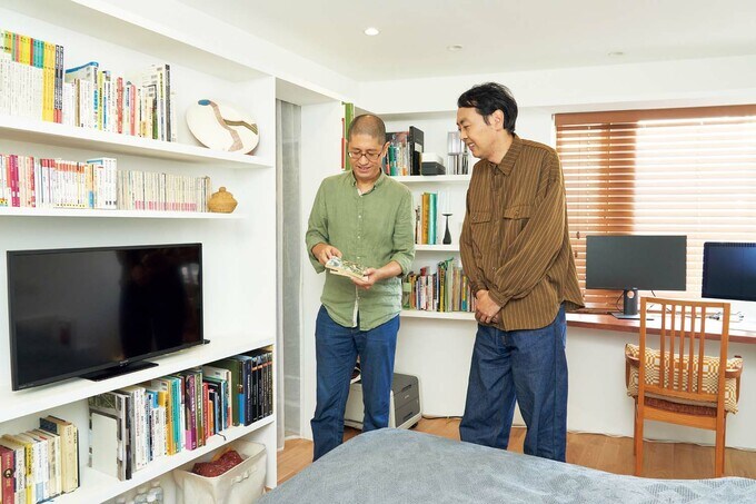 壁面につくりつけた本棚の前で語り合う2人