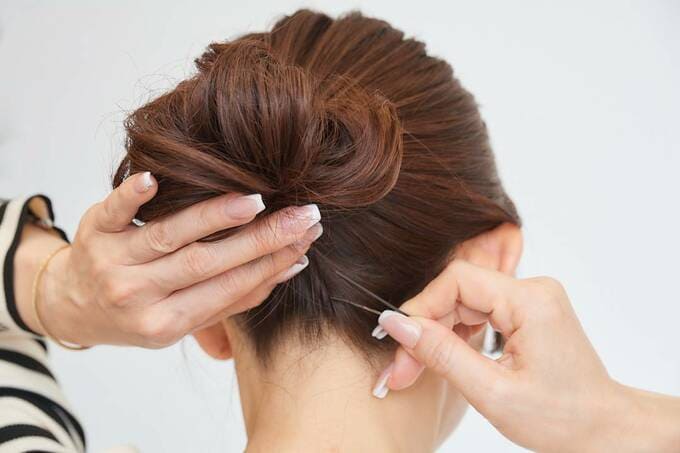 えり足の毛をピンでおさえている女性