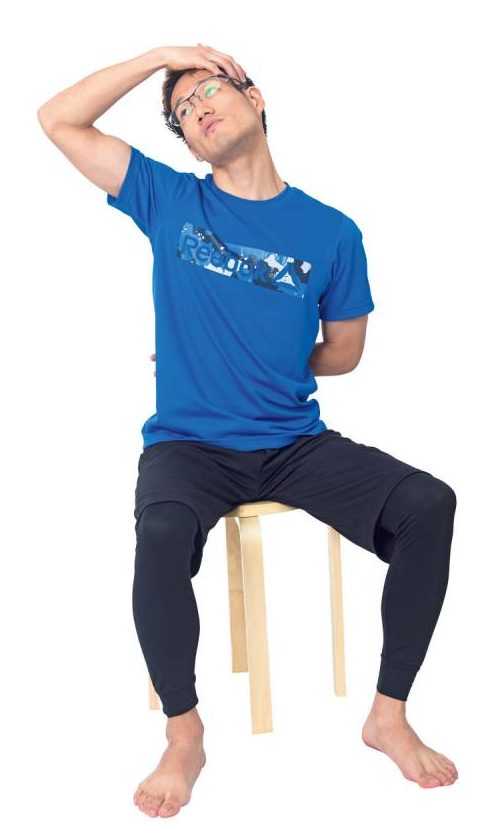 イスに座って右手を左耳の上に当てる男性