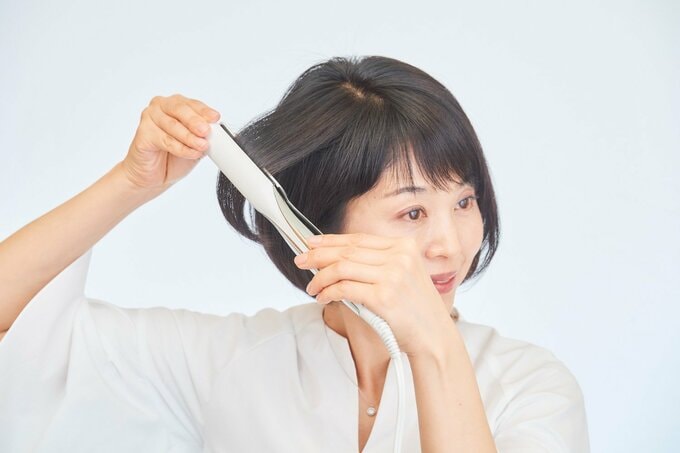 ヘアアイロンをあてる女性