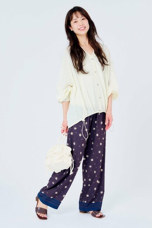 カバンを持って微笑んで立つ女性