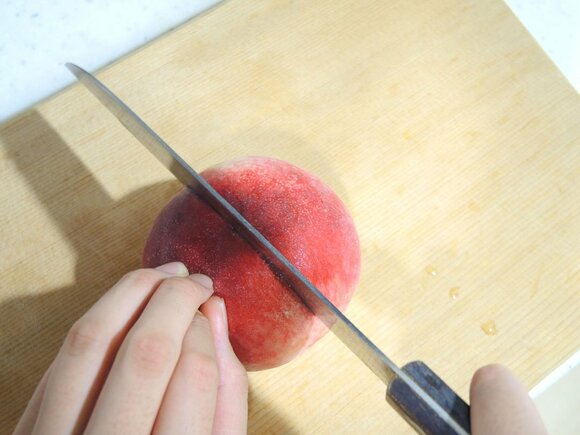 白桃の割れ目に沿って包丁を入れ、360度切れ目を入れる