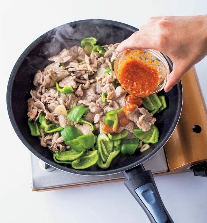 フライパンに調味料を加える様子