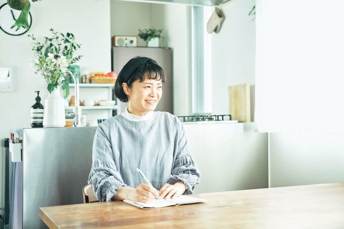 ダイニングテーブルでメモを取る女性