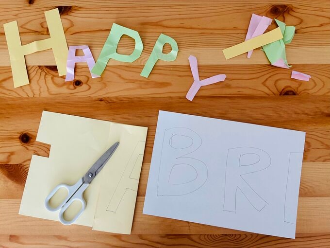 HAPPY BIRTHDAYの文字を折り紙から切り抜いている