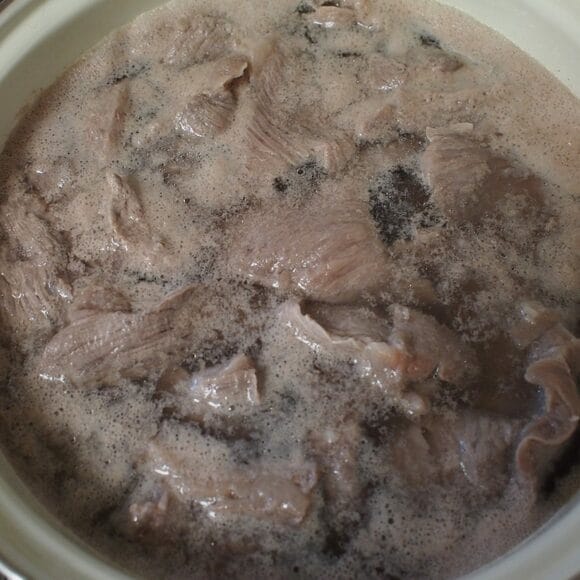 牛すじをザルにあげて水洗いする。