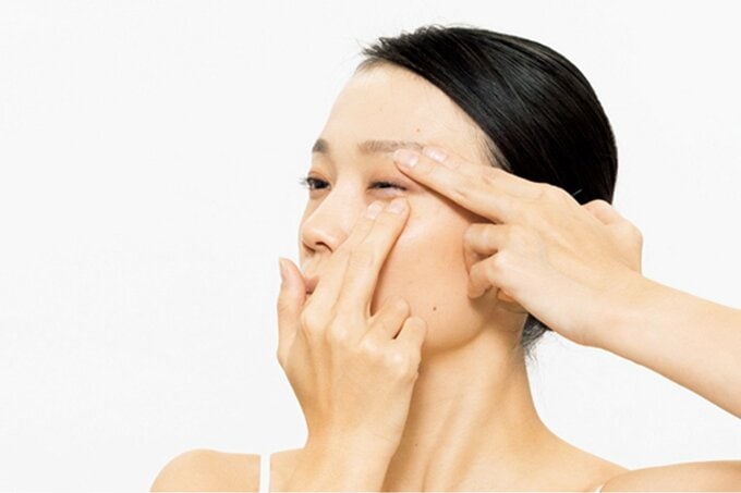 まぶたに指を当て目を閉じようとしている女性