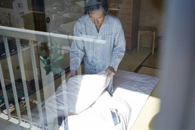 布団を持つパジャマを着た男性