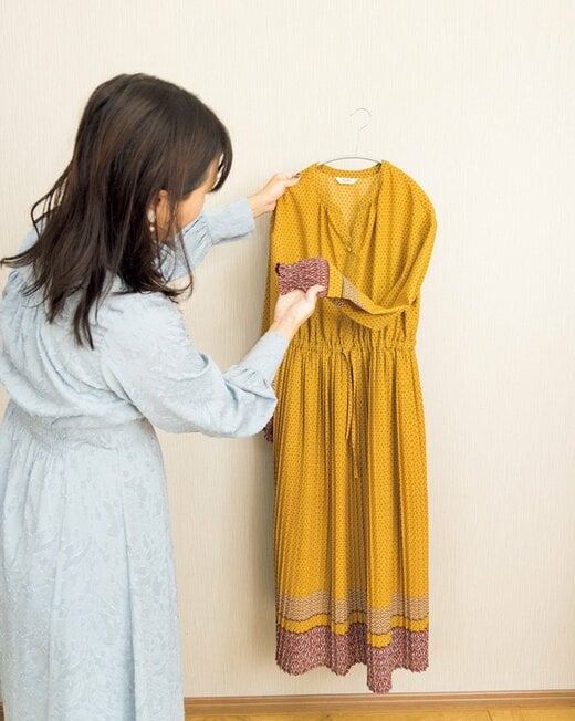 女性が黄色いワンピースを確かめる様子