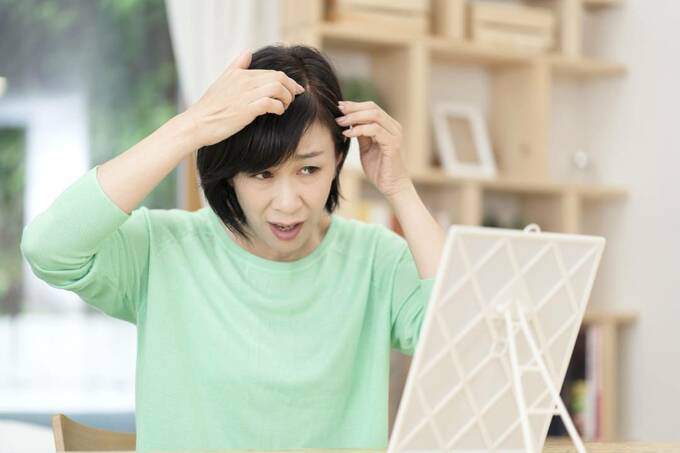 鏡の前で髪をおさえる女性