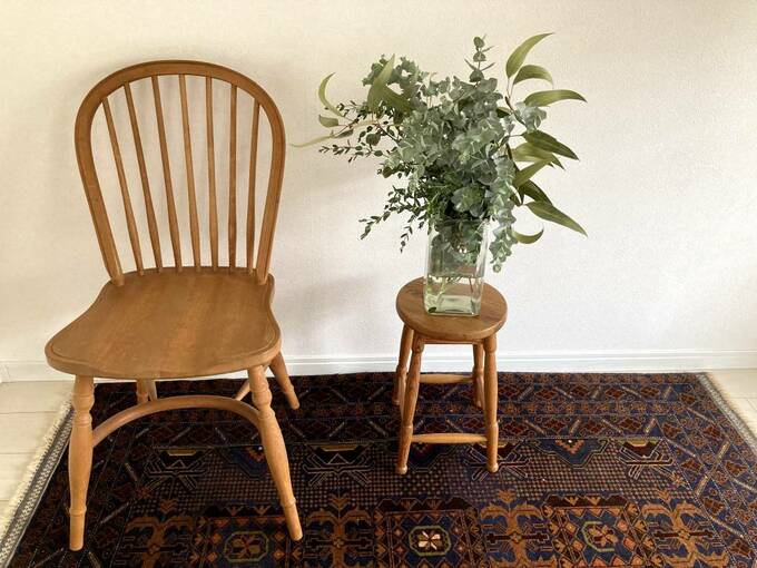 チェアとスツールの上にユーカリの挿してある花瓶が置いてある