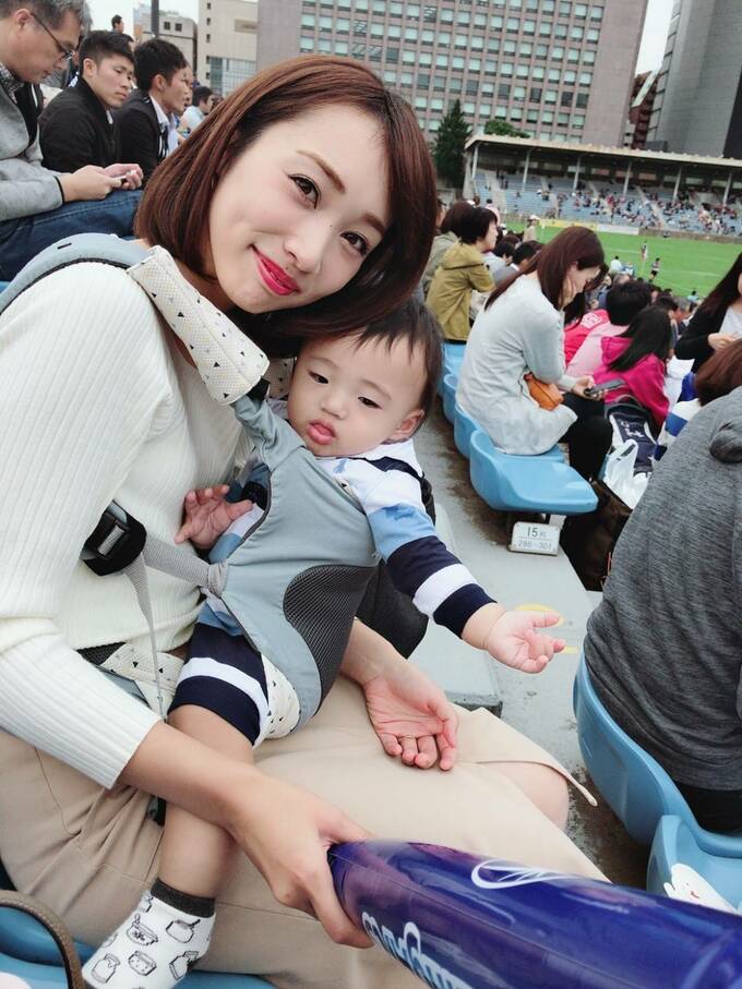 女性が子供を抱いて試合を観戦している様子