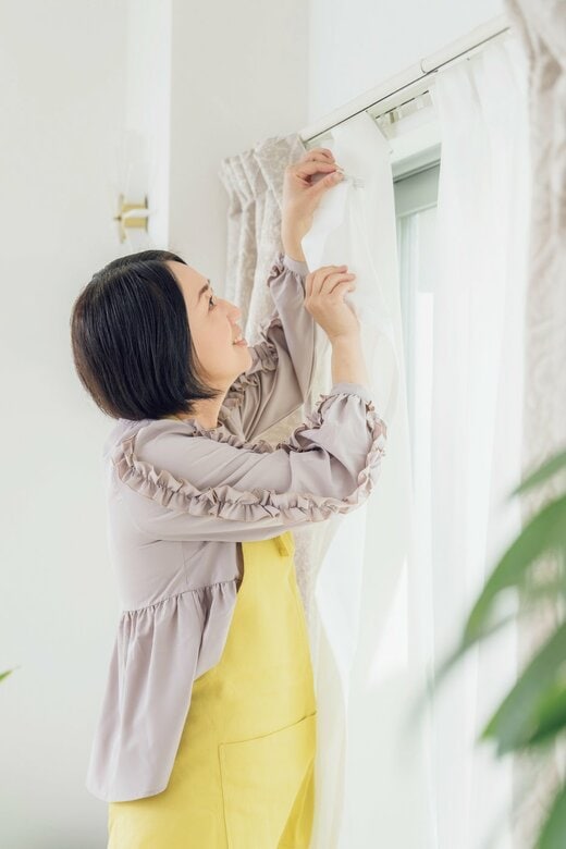 女性がレースカーテンをつける様子