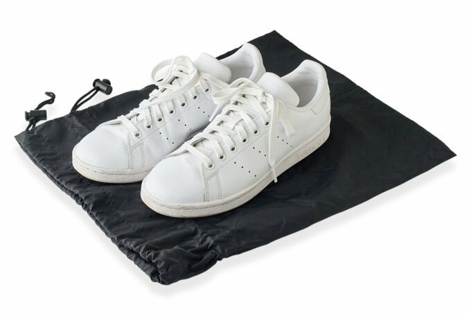 靴袋の上に置かれた革製のスニーカー