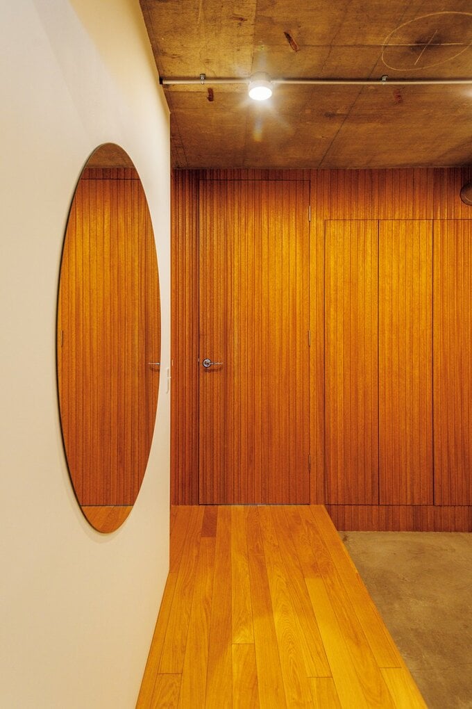 木のリブパネルを張った扉と壁が印象的な玄関