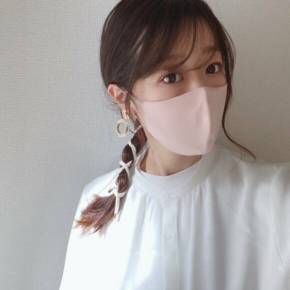 パステルピンクのマスクをつけた髪をヒモで巻いた女性