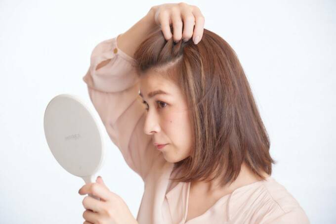鏡を見ながら髪を触る女性