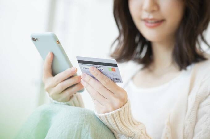 スマホとカードを持つ女性