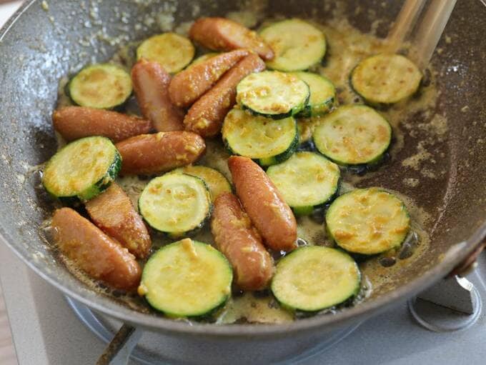 フライパンにズッキーニとウインナーに調味料