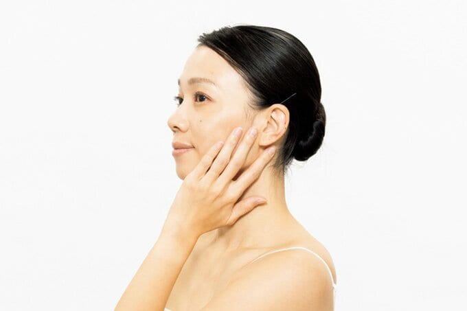 頬に手を当て横を向く女性