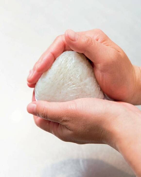 おにぎりをラップで包んでにぎっている様子