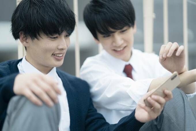 スマホを持つ制服の男性2人