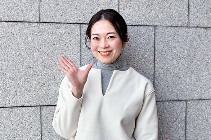 笑顔で片手をあげるEmiさん