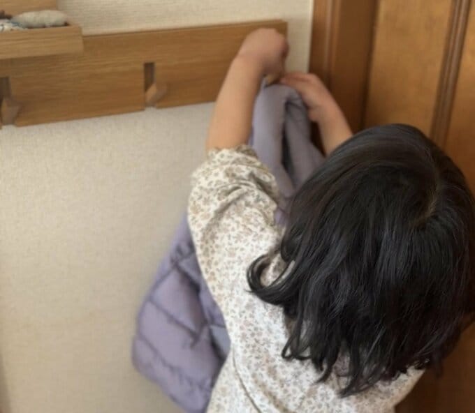 子どもが服をフックにかける様子