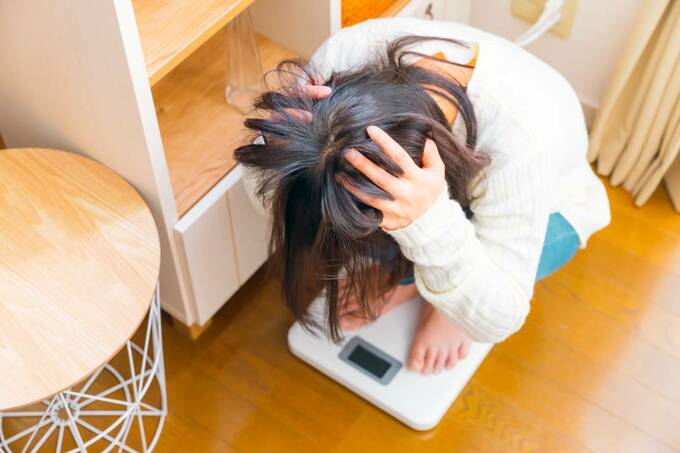 体重計の上で頭を抱える女性