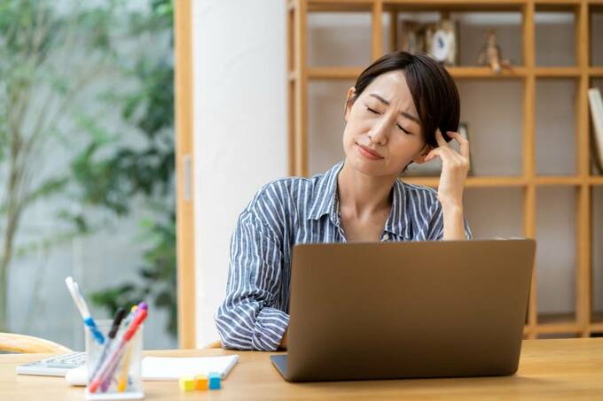 パソコンの前で頭おさえる女性