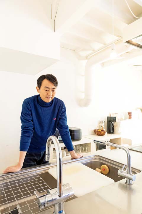 リビングと一体化したキッチンを見る田中さん