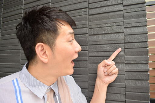 外壁のサイディングを指差すコジマジックさん