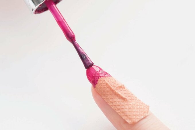 ばんそうこうを貼った指にマニキュアを塗る